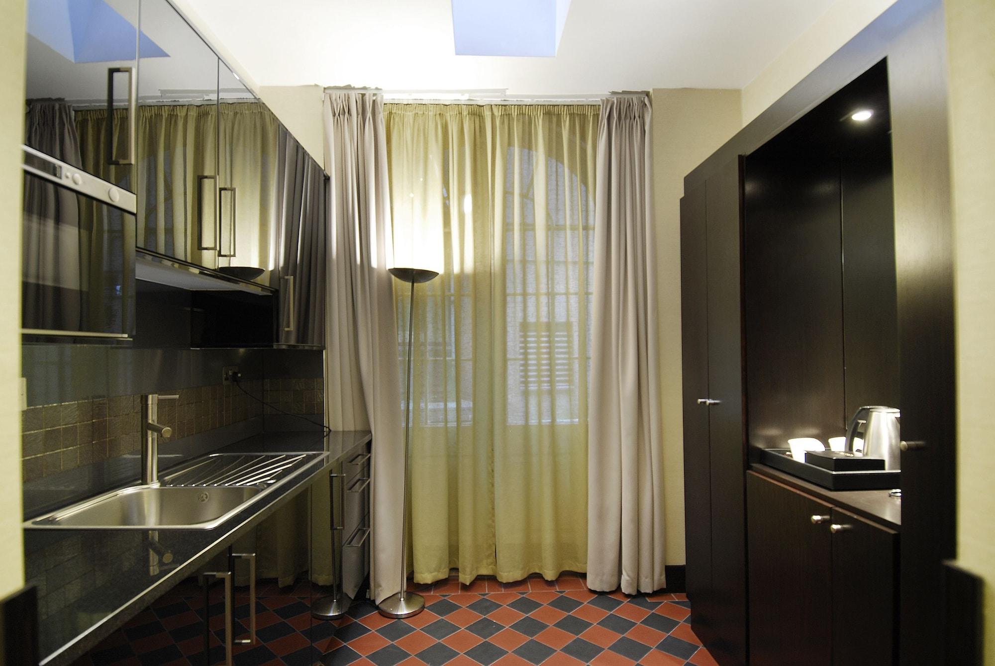 Montcalm Brewery Townhouse Hotel London Exterior photo The photo shows a modern kitchen space. On the left side, there is a sleek countertop and kitchen cabinets in a dark finish. The backsplash appears shiny, reflecting the surroundings. To the right, there is a tall black cabinet. A window is covered w