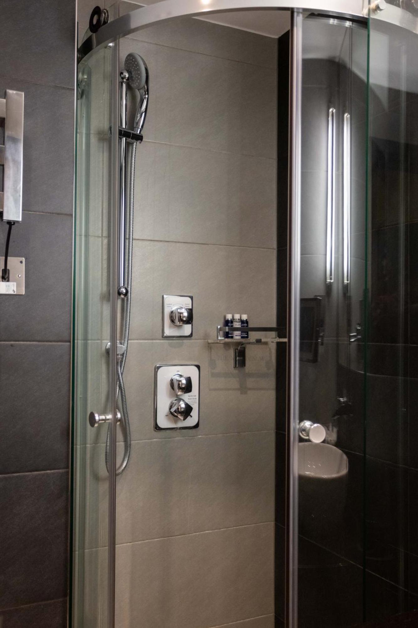 Montcalm Brewery Townhouse Hotel London Exterior photo The photo shows a modern shower area. It features glass panels and tiled walls in a neutral color palette, creating a sleek and contemporary look. There are two main control panels for adjusting the water temperature and pressure, with various knobs 