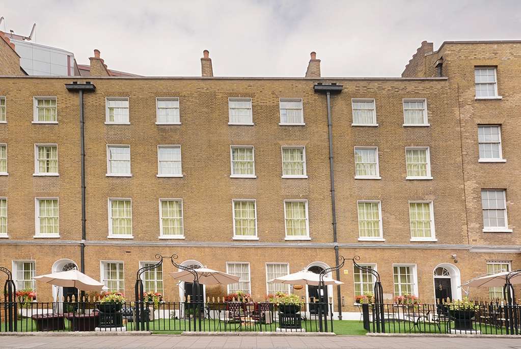 Montcalm Brewery Townhouse Hotel London Exterior photo The photo shows a brick building with several windows on its facade. The structure appears to be three stories tall, featuring a symmetrical design with multiple windows that have white frames. In front of the building, there is a landscaped area wit