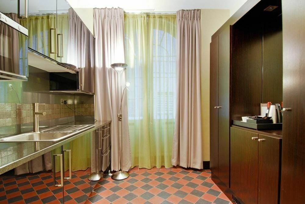 Montcalm Brewery Townhouse Hotel London Exterior photo The photo shows a modern kitchen area. There is metallic cabinetry and a stainless steel countertop with a sink. The walls are adorned with light-colored curtains that allow natural light to filter in, with one set in a soft purple hue and another in